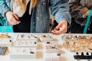 Person sorting through jewelry at craft market.