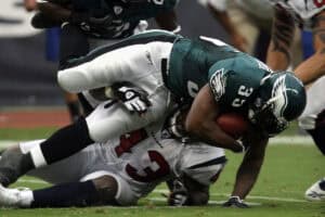 Football player tackling opponent on field.