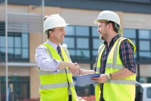 Construction workers shaking hands at a building s.