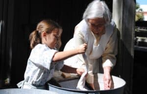 Child and elderly woman engaging in pioneer craft.