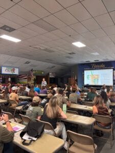 Audience at youth steer sale event at fairgrounds.